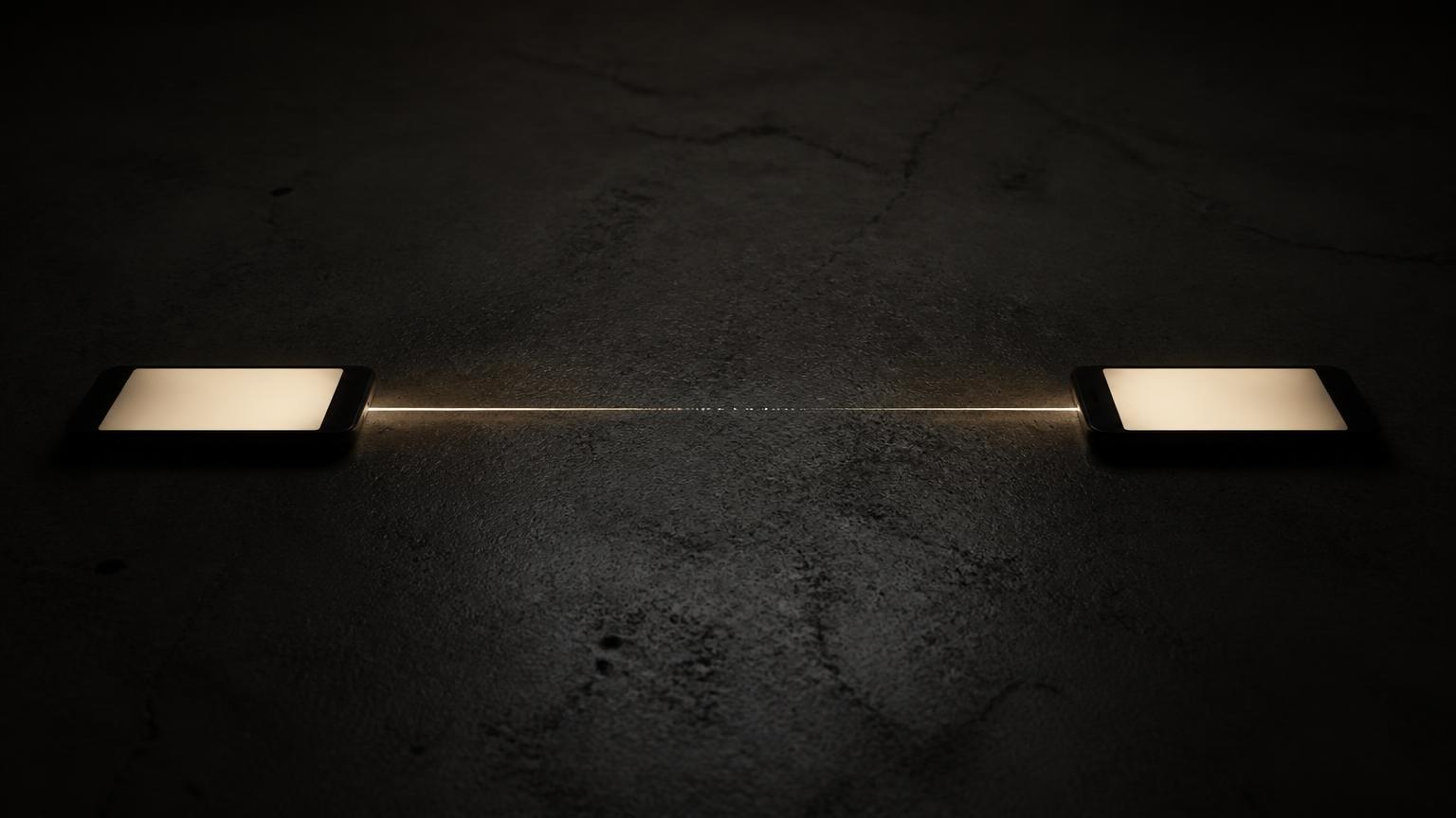 Two devices facing each other in low light, the line of light between them thinning until it is barely present